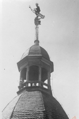 Dachdecker beim Streichen der Wetterfahne auf der Kirchturmspitze
